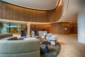 Un vestíbulo moderno con paneles de madera curvados, un mostrador de recepción y una distribución de asientos contemporánea.