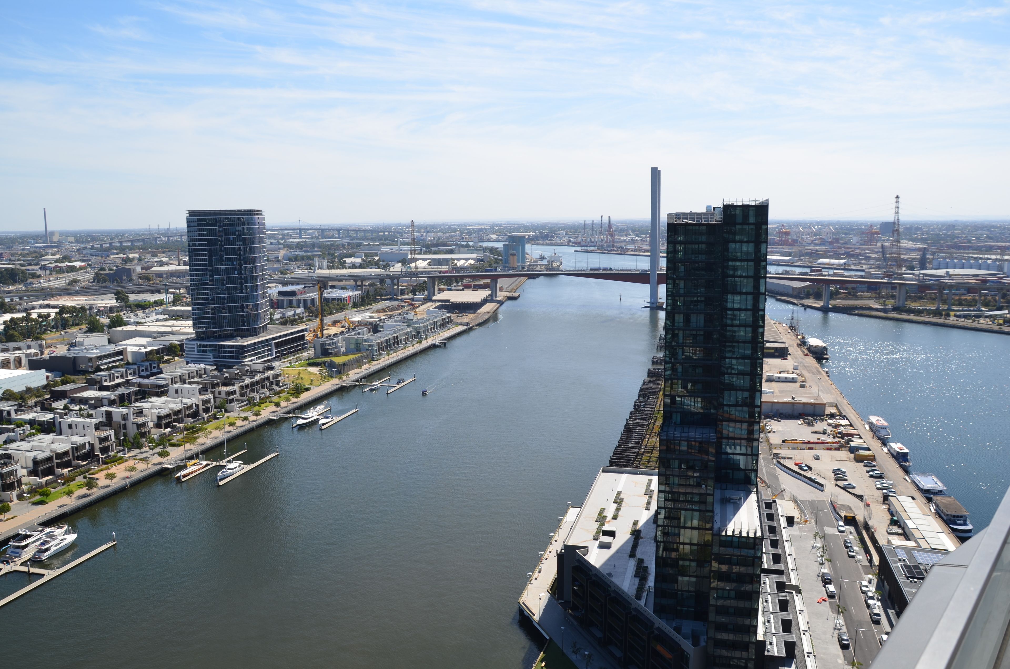 A modern cityscape with a river, two prominent skyscrapers, and a bridge in the background.