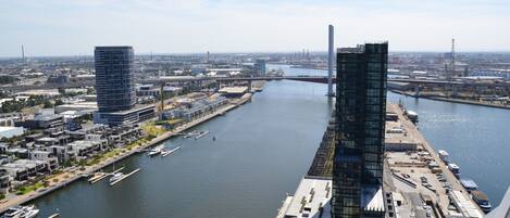 A modern cityscape with a river, two prominent skyscrapers, and a bridge in the background.