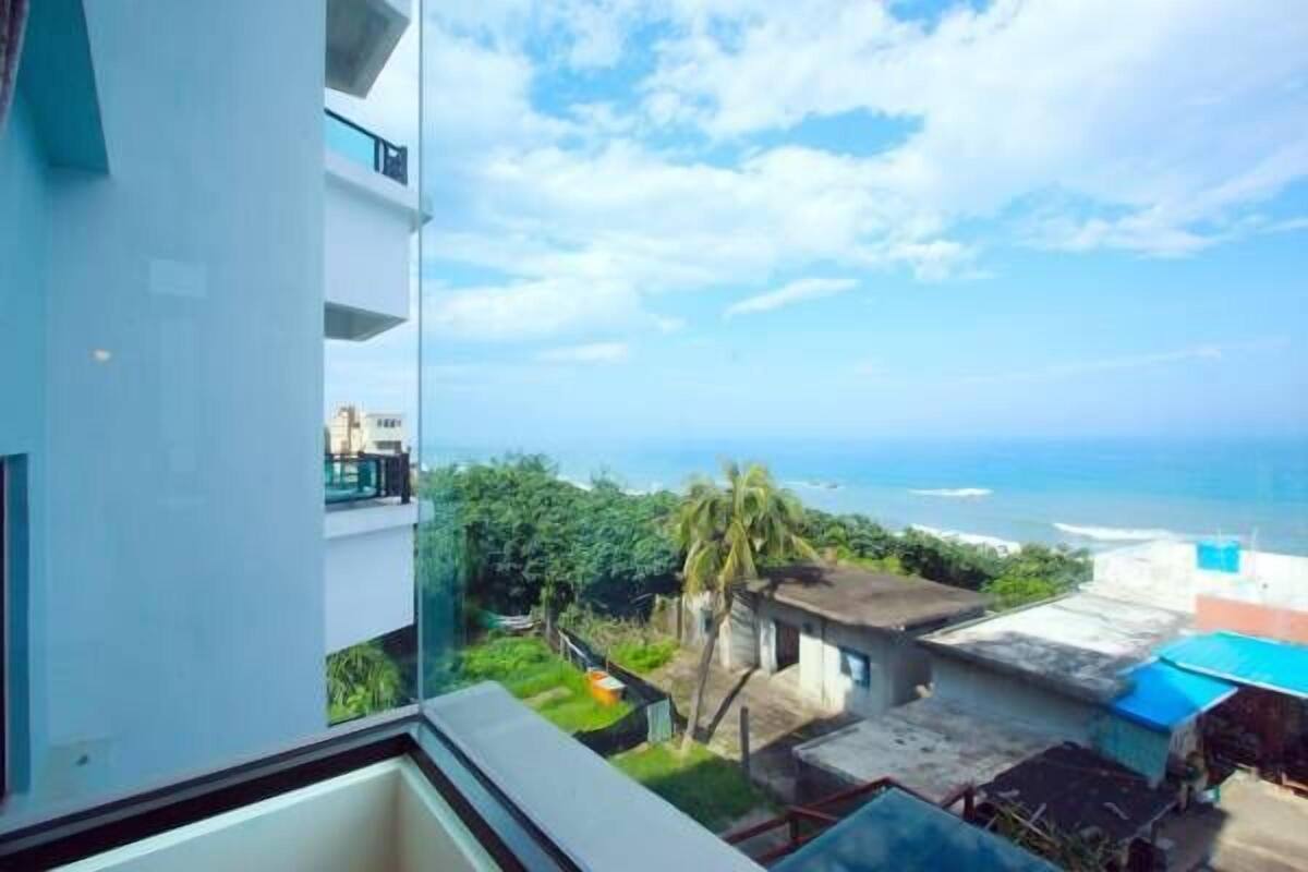 A balcony with a view of the ocean and a residential area.