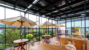 A spacious indoor area with large windows, wooden tables and chairs, and multiple umbrellas. - Water Ripple B&B (Shoufeng)