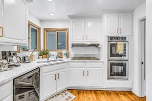 A kitchen with white cabinetry, a built-in oven, and a dishwasher. - FamilyRetreat, IndoorSpaTub, NewAC, 5mins walk2village, LakeAccess, Sleep15 (Lake Arrowhead)