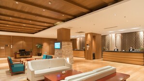 A modern hotel lobby with a reception desk, seating area, and a television screen. - Genting Grand Chongli (Zhangjiakou)