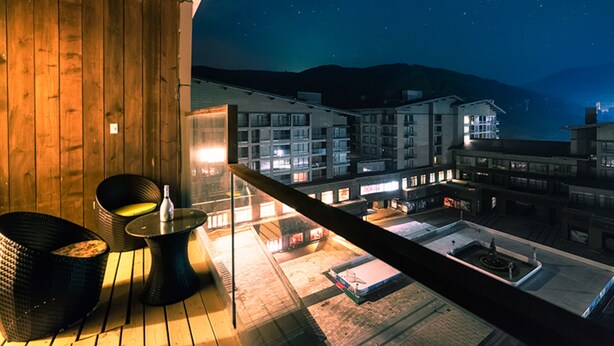 A balcony with a wooden floor, two black chairs, and a small table. - Genting Grand Chongli (Zhangjiakou)