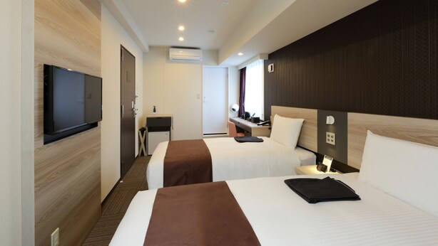 Een hotelkamer met twee bedden, een televisie, een bureau en een badkamer.