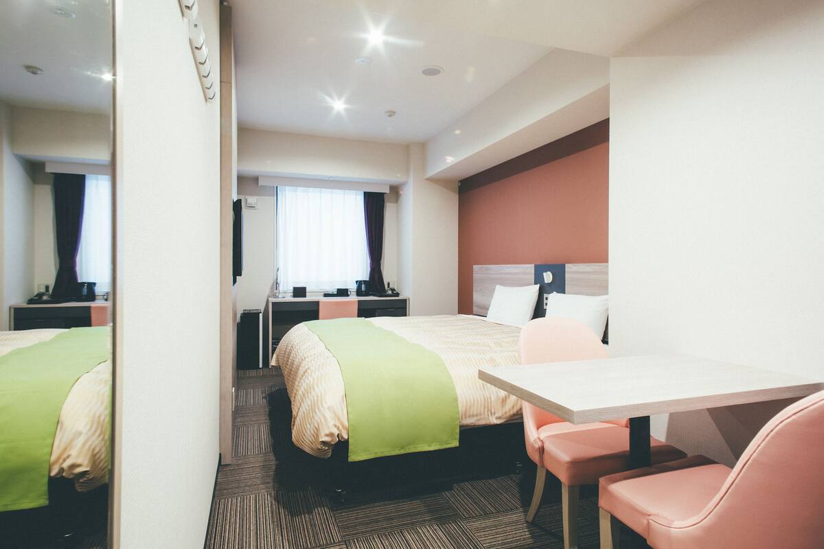 A hotel room with two beds, a desk, and a chair.