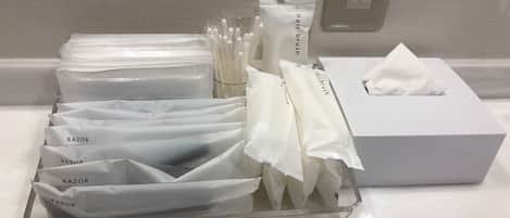 Una encimera de baño con un estuche para afeitar, un cepillo para el cabello y una caja de pañuelos.