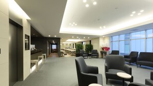 Een moderne lobby met een receptiebalie, een zithoek en grote ramen.