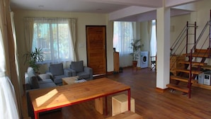 A spacious living area with a wooden table, a sofa set, and a staircase. - Lazimpat House B&B (Kathmandu)