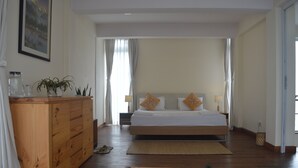A bedroom with a wooden dresser, a bed with pillows, a nightstand, and a small plant on the floor. - Lazimpat House B&B (Kathmandu)
