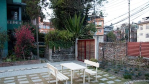 A patio with stone flooring and wooden furniture. - Lazimpat House B&B (Kathmandu)