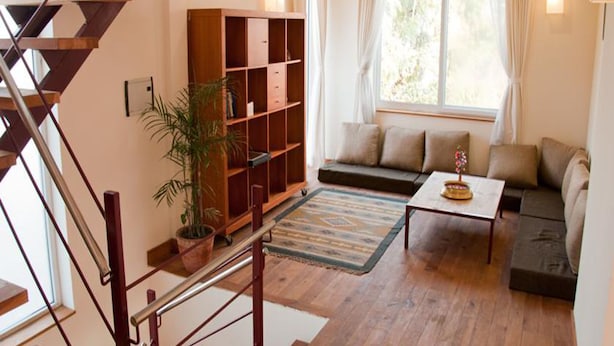 A modern living room with a staircase, a bookshelf, a sofa, and a coffee table. - Lazimpat House B&B (Kathmandu)