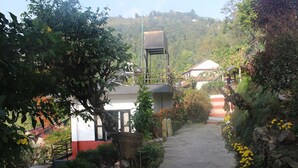 A pathway leading to a building surrounded by greenery and flowers. - Siddhartha Garden (Pokhara)