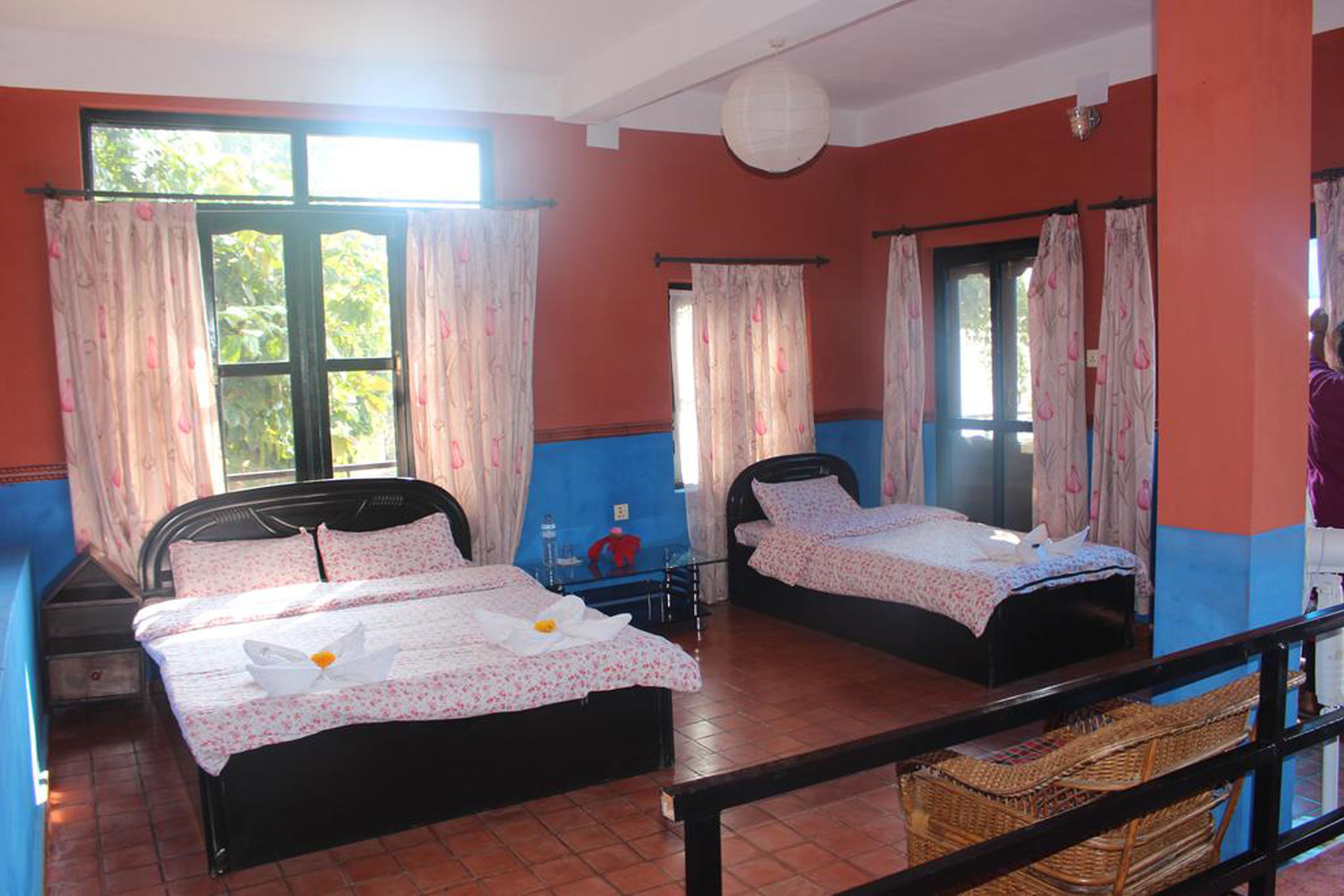 A hotel room with two beds, a small table, and a window with curtains.