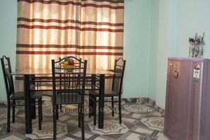 A dining area with a table and chairs, a fruit bowl, and a refrigerator. - Sahara Apartment (Kathmandu)