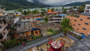 Une terrasse avec une table et des chaises, d’où l’on a vue sur une ville avec ses bâtiments et un lac.