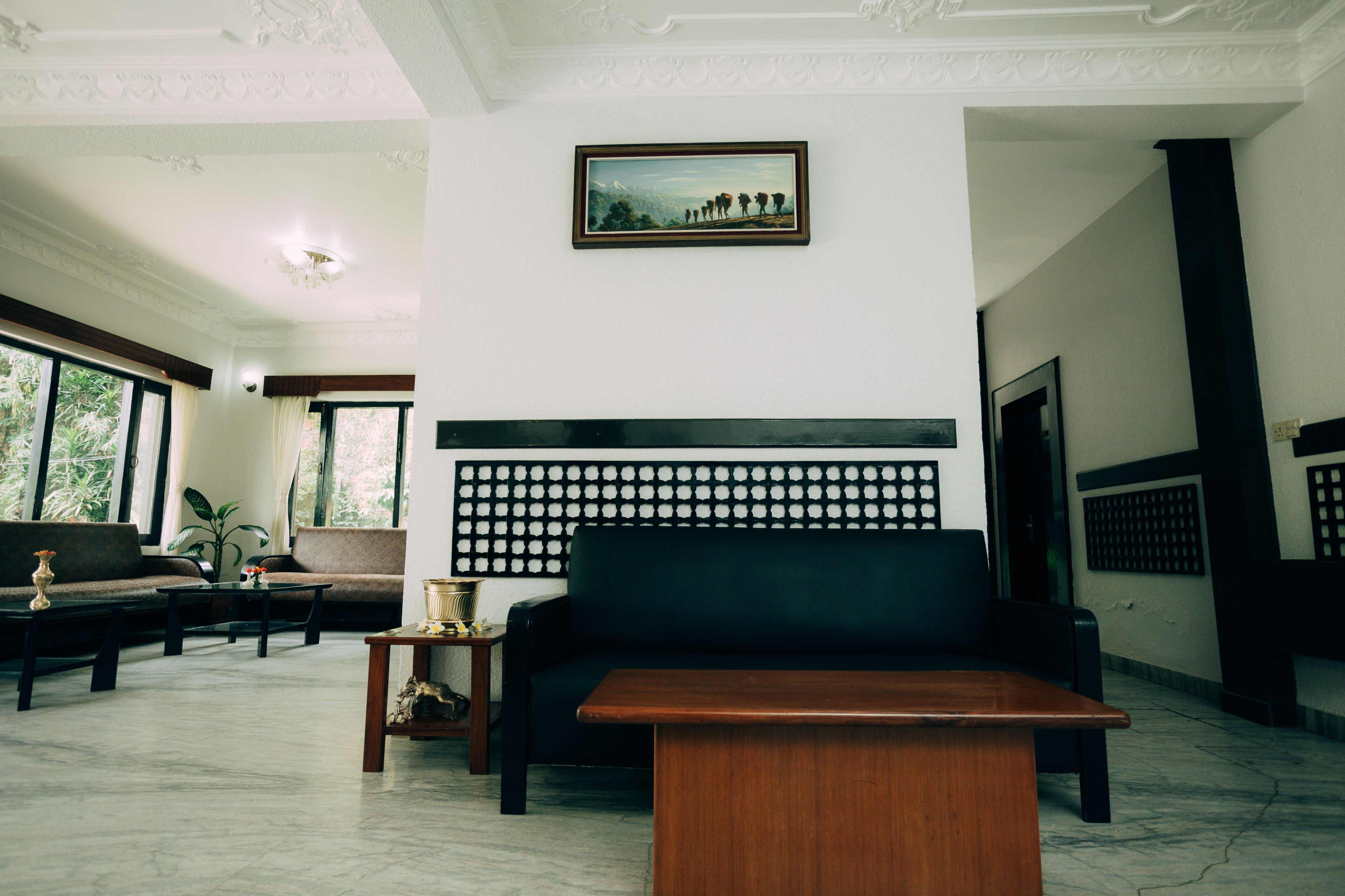 Un vestíbulo moderno con un sofá negro, una mesa de centro de madera y un papel tapiz estampado.