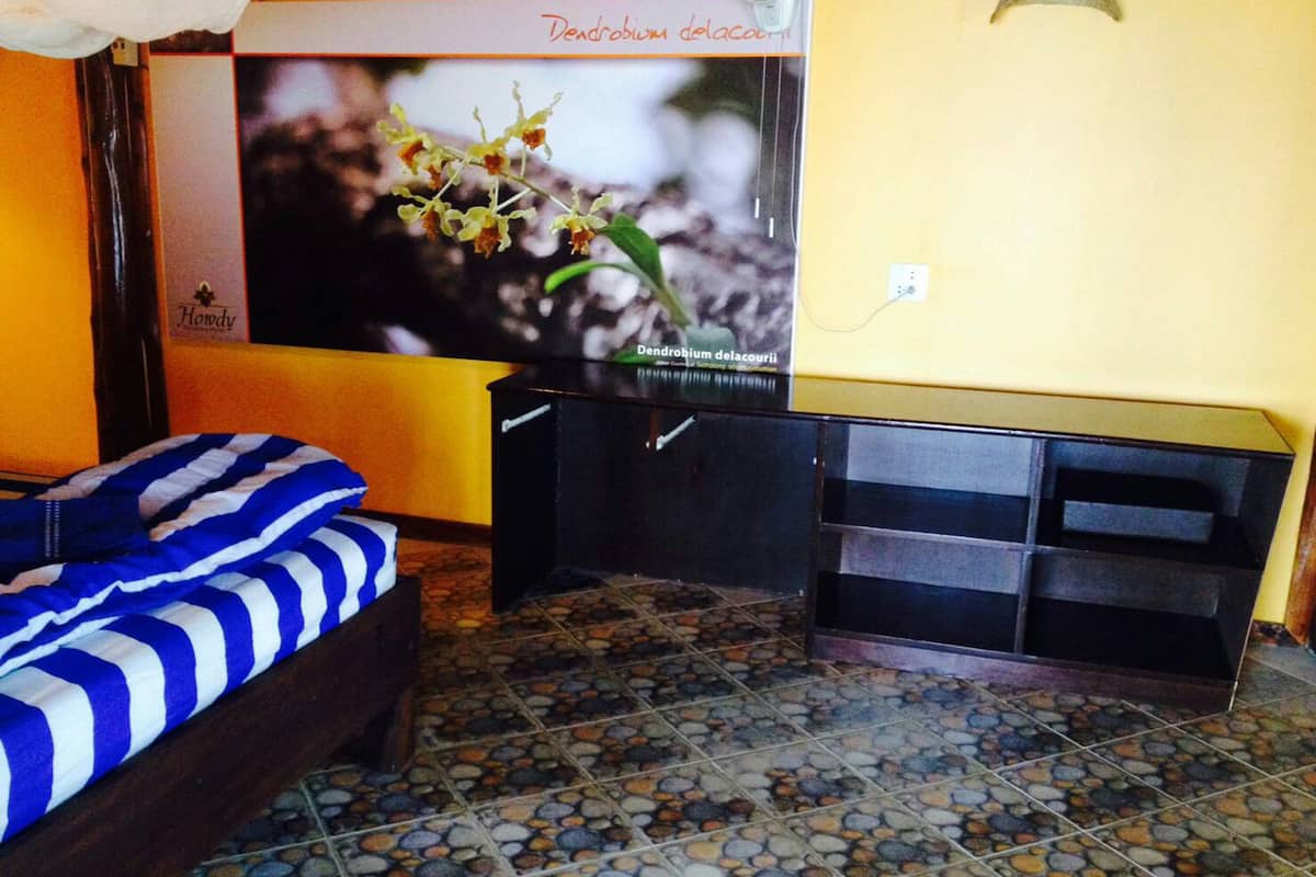 Una habitación con cama, televisión y piso de baldosas.