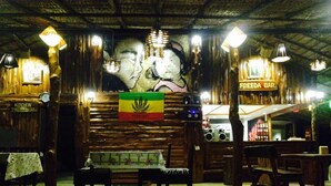 A rustic interior with wooden walls, a mural, a flag, and a bar area.