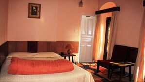 A hotel room with two beds, a small table with a lamp, a chair, and a door leading to another room. - Hotel Shakti (Kathmandu)