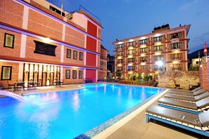 Ein Hotel mit Pool, Außenbereich und einer gut beleuchteten Fassade.