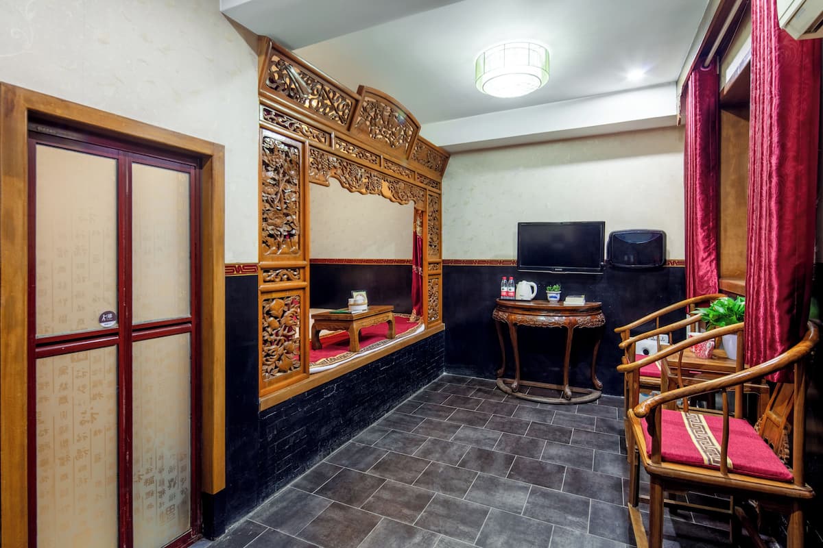 A traditional room with a wooden partition, a television, a small table with a plant, and a red curtain.