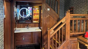 Una scala in legno con corrimano, una porta in legno e uno specchio con luce circolare.