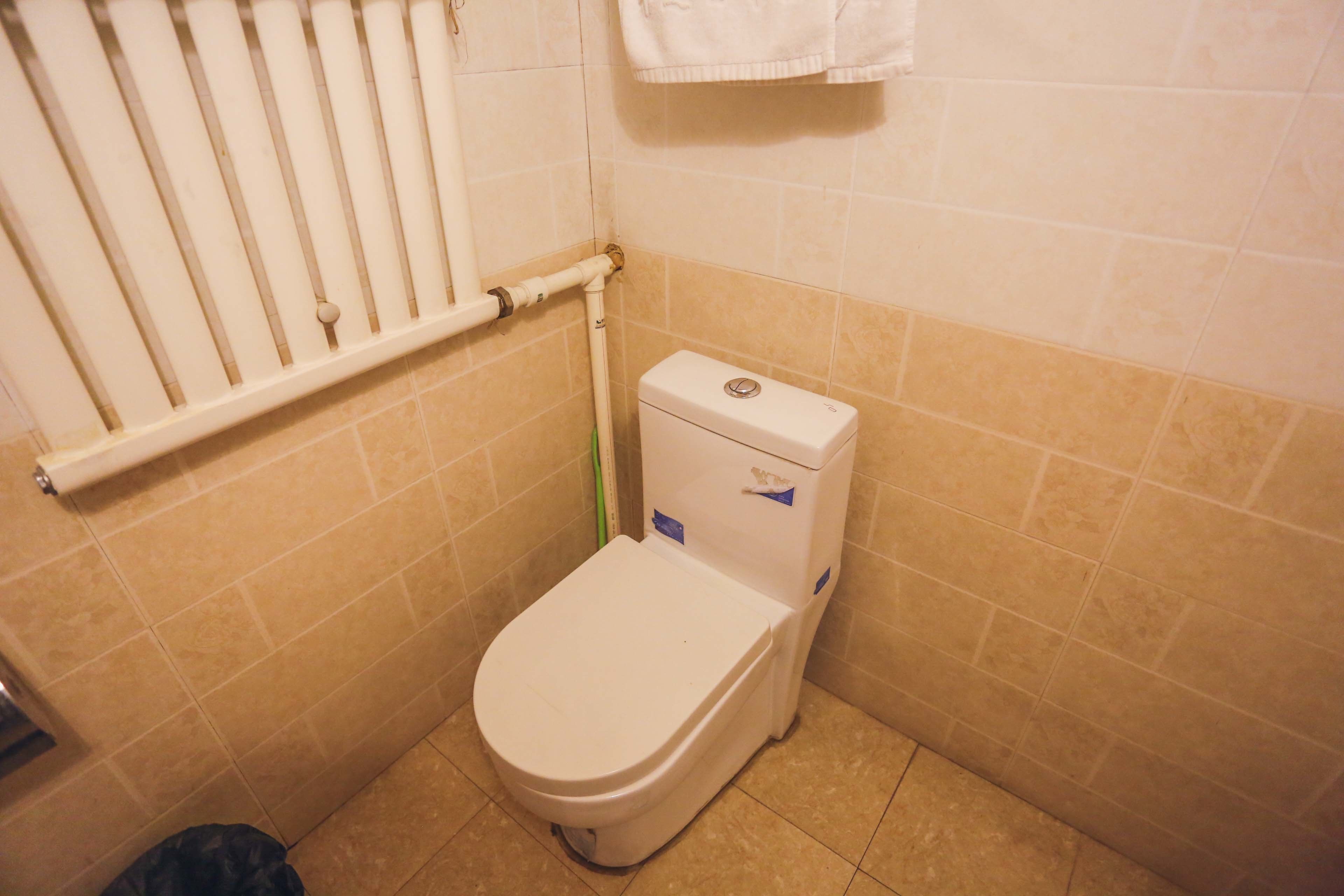 A small bathroom with a toilet, a towel rack, and a toilet paper holder.