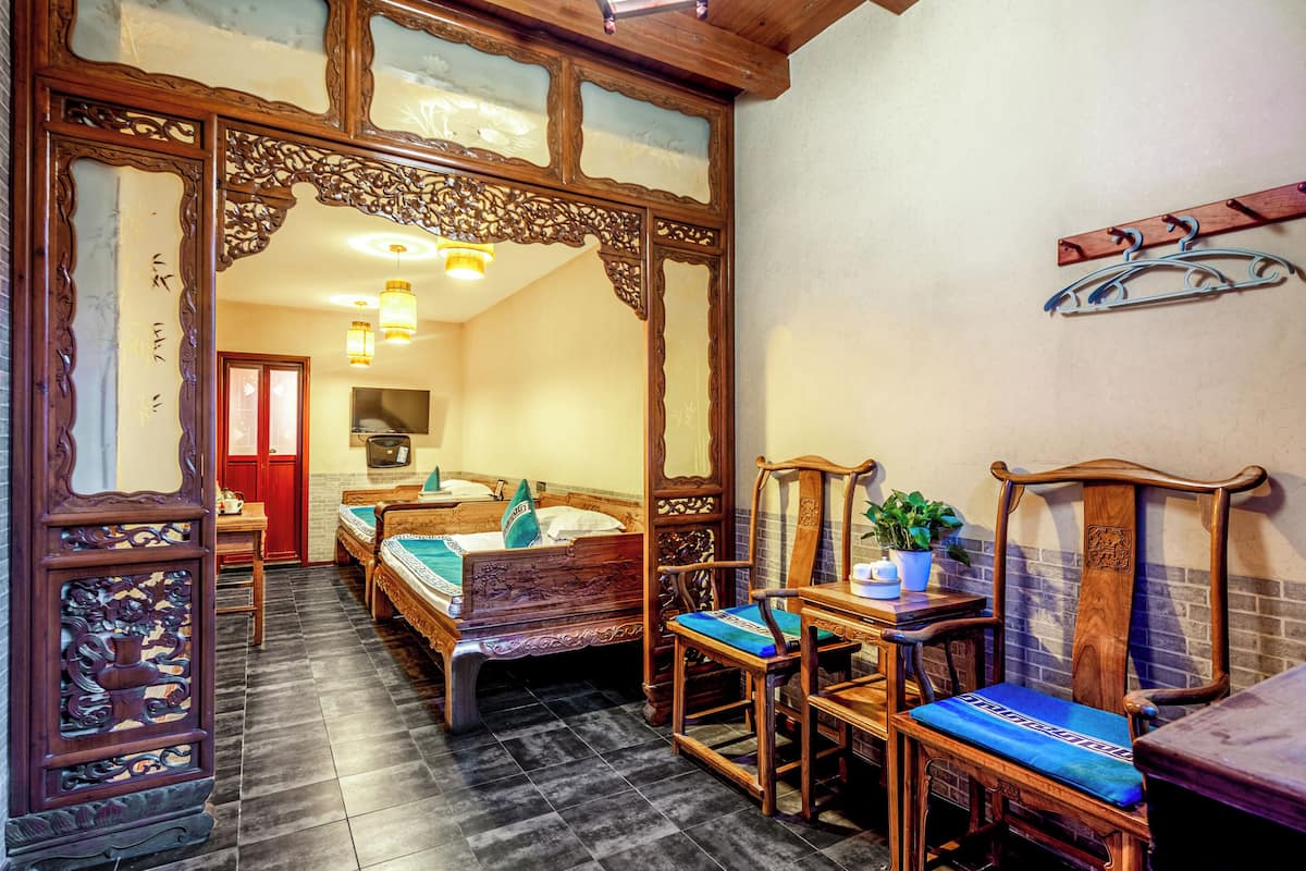A traditional room with two wooden beds, a wooden chair, a table, and a mirror.