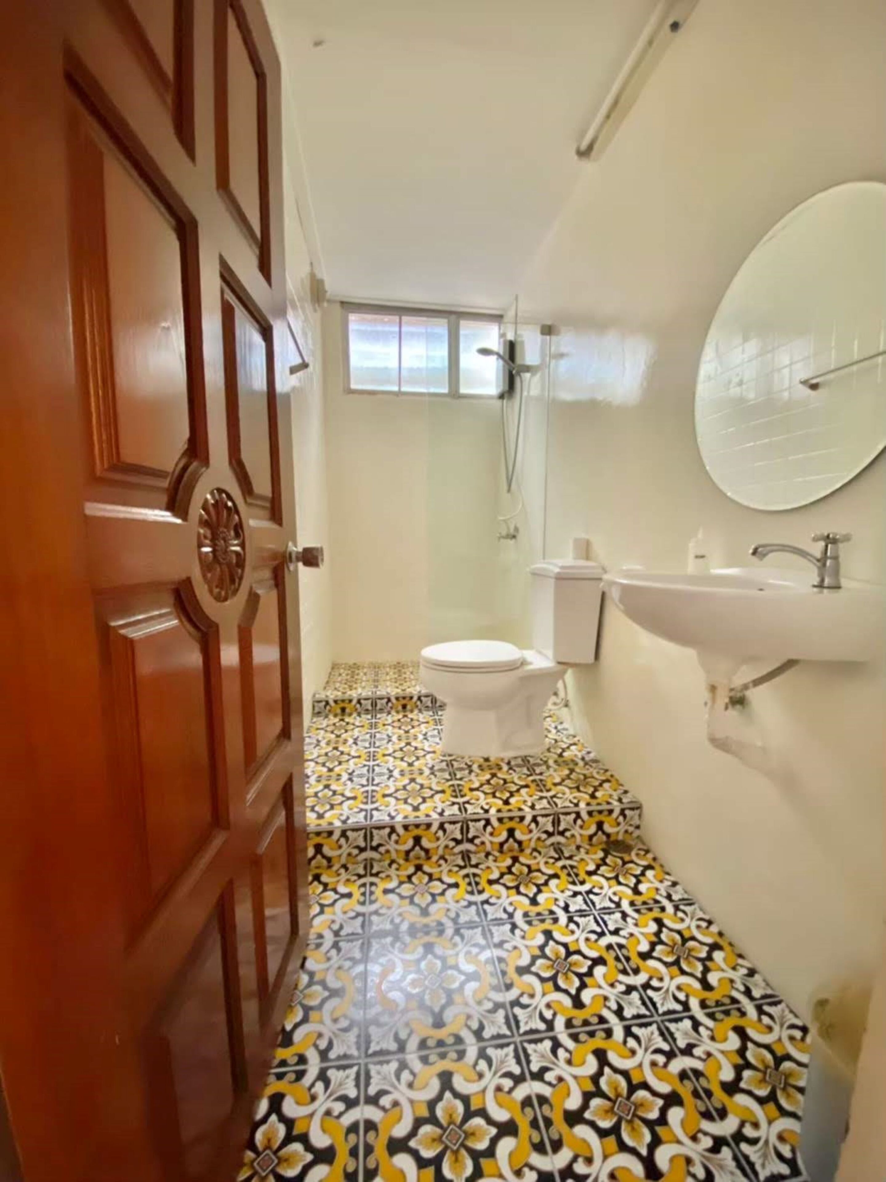 Un baño con baldosas estampadas, un inodoro, un lavabo y un espejo.