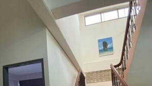 A staircase with a wooden handrail and metal balusters, leading to a room with a bed and a window. - No.7 Guesthouse (Krabi)