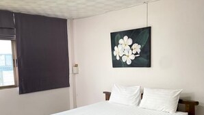A bedroom with a bed, a window with curtains, a painting of flowers, and a ceiling light. - No.7 Guesthouse (Krabi)