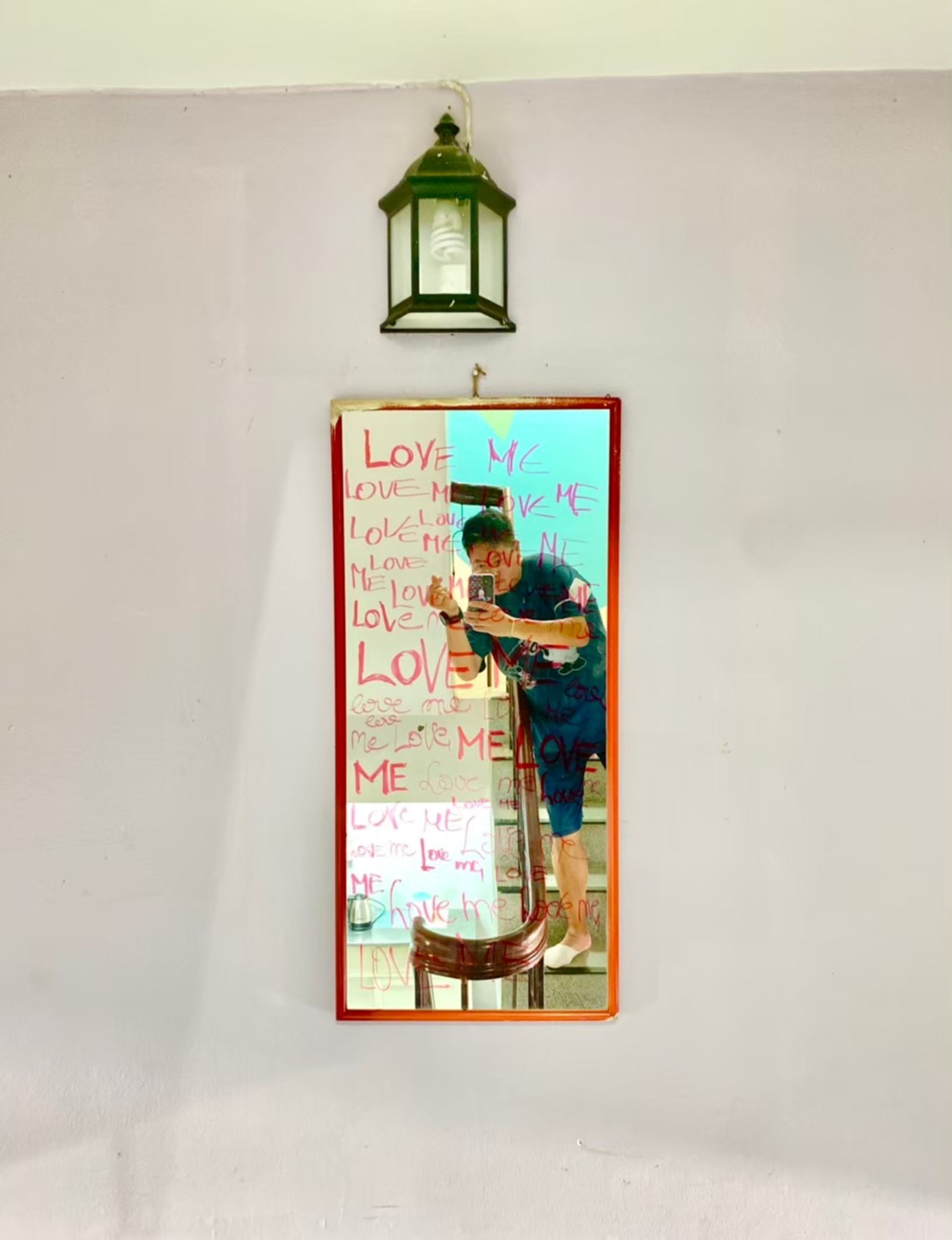 A wall-mounted mirror with a person taking a selfie.