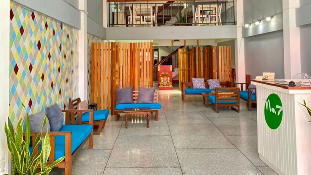 A spacious lobby with a high ceiling, a staircase leading to an upper level, and a reception desk. - No.7 Guesthouse (Krabi)