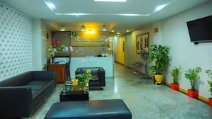 A hotel lobby with a reception desk, sofas, a coffee table, and potted plants. - Sebong Hotel (Hanoi)