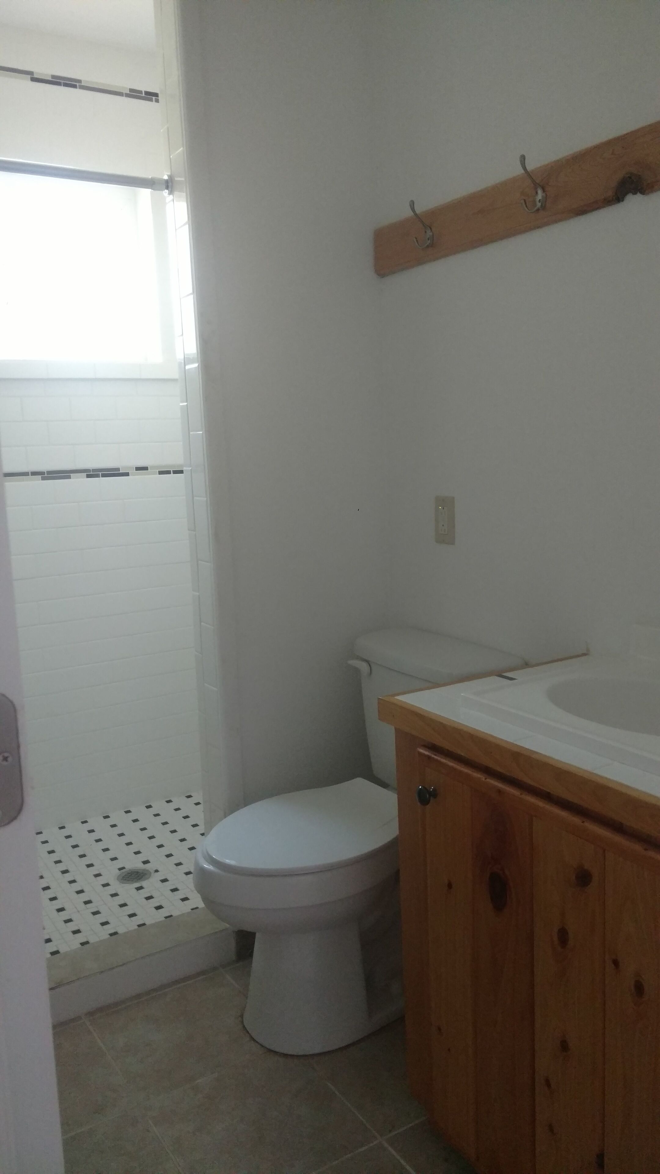 Une salle de bain comprenant des toilettes, un meuble en bois et un espace douche avec un sol carrelé.