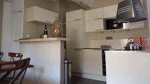 Una cuina amb armaris blancs, una campana extractora d'acer inoxidable i un búllet a la tauleta.