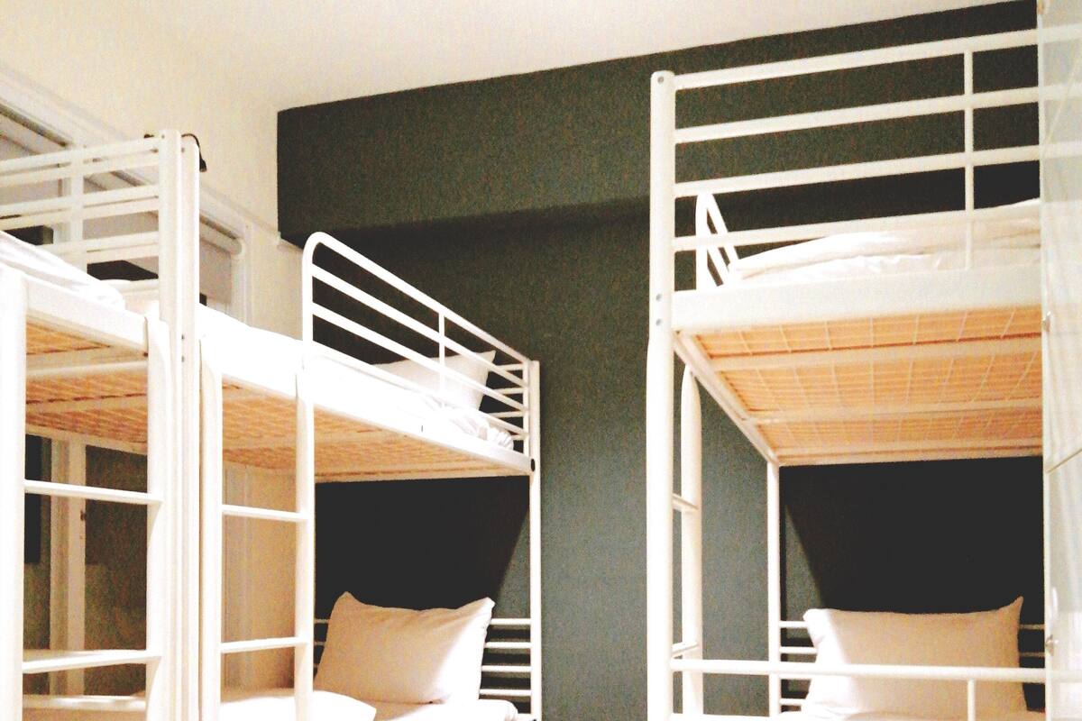 A room with two bunk beds, wooden flooring, and a dark-colored wall.