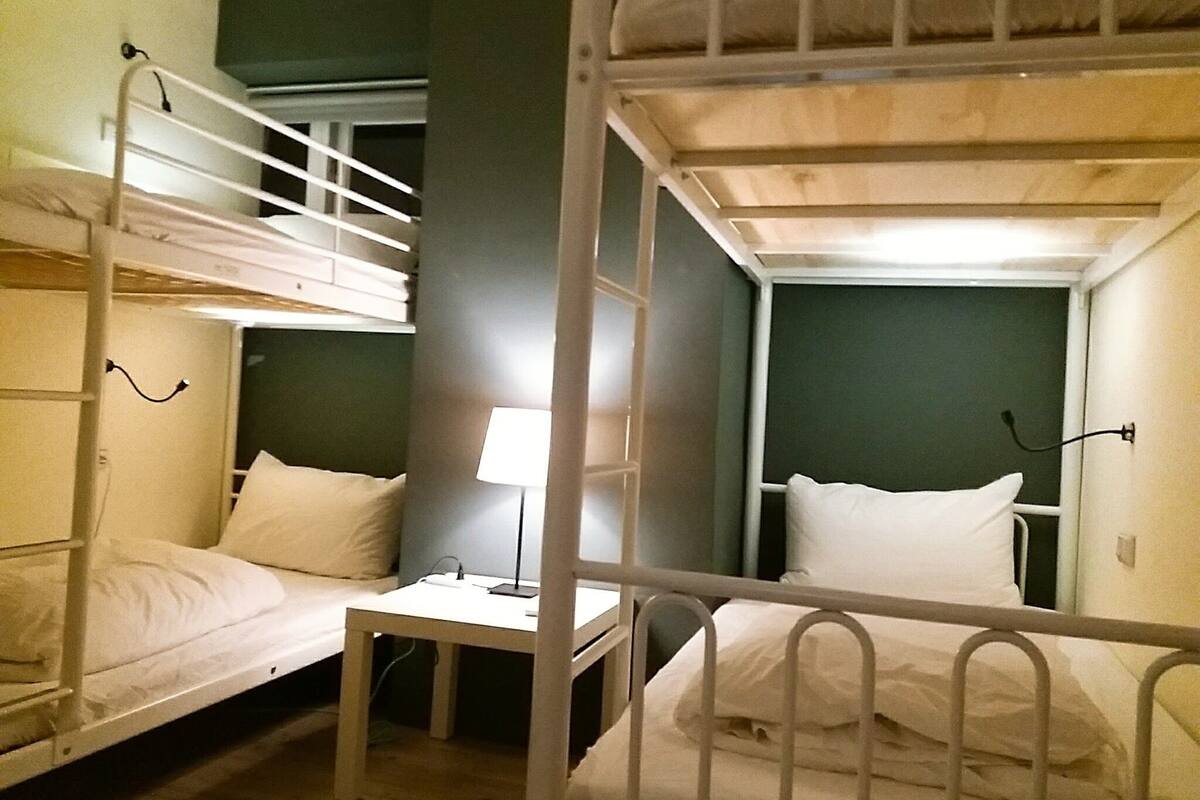 A bunk bed room with a small table and a lamp.