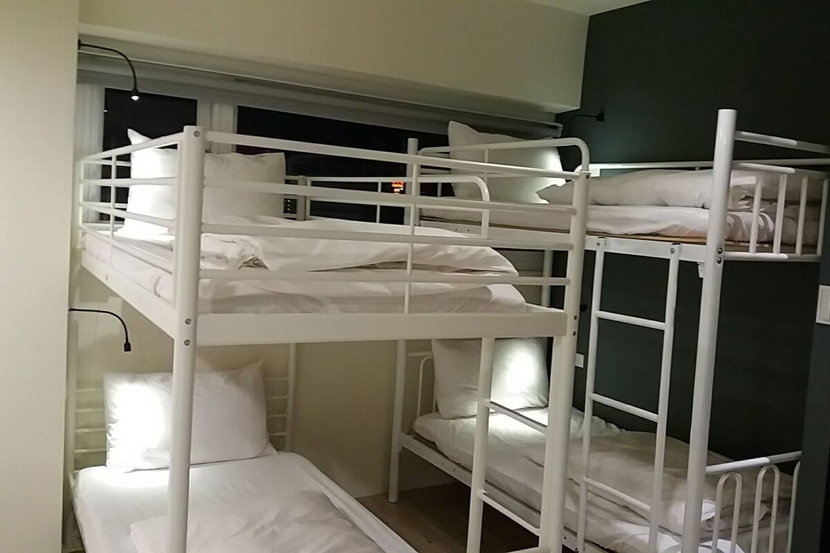 A bunk bed room with white bedding and a dark green wall.
