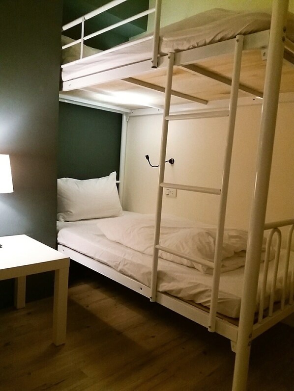 Habitación con literas, una mesita pequeña y un enchufe de pared.