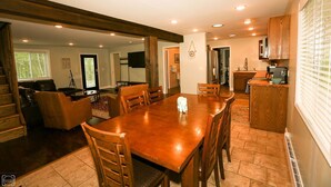Un comedor amplio con una mesa y sillas de madera, una cocina con armarios de madera, y una sala de estar con chimenea.