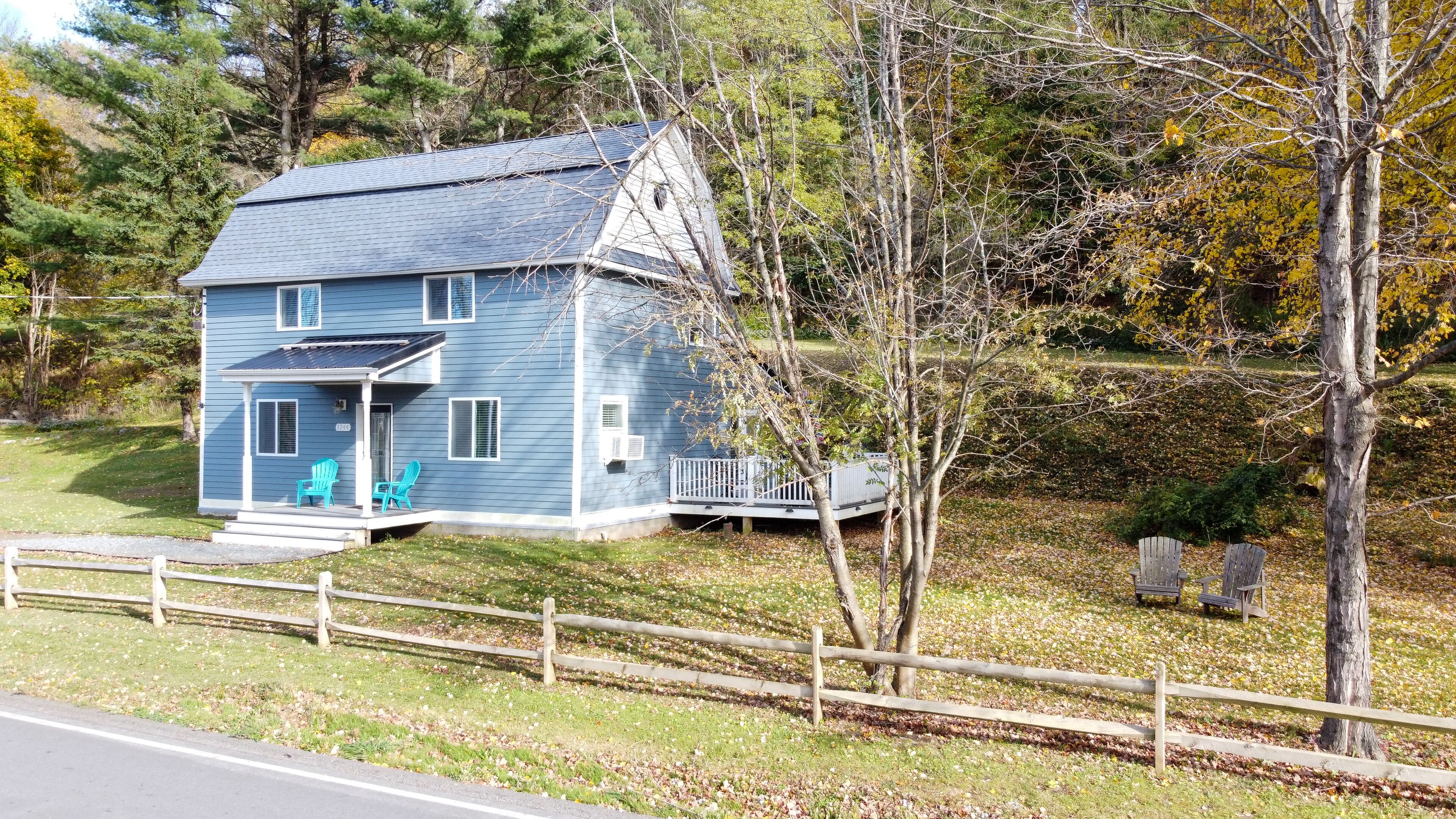 A two-story house with a porch, a small deck, and a fenced yard.