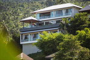 A multi-story building with balconies, surrounded by lush greenery.