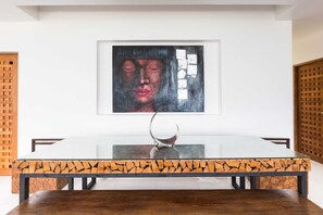 A dining area with a white table, black and orange patterned table base, and a modern sculpture centerpiece.