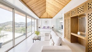 Una sala de estar moderna con un ventanal grande, techo de madera y un sofá.
