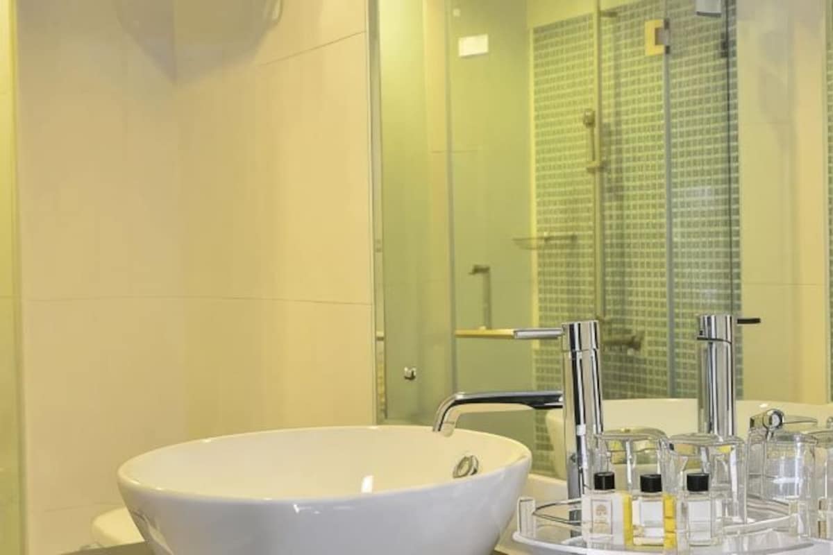 Un baño con lavamanos blanco, cabina de ducha de vidrio y un espejo.