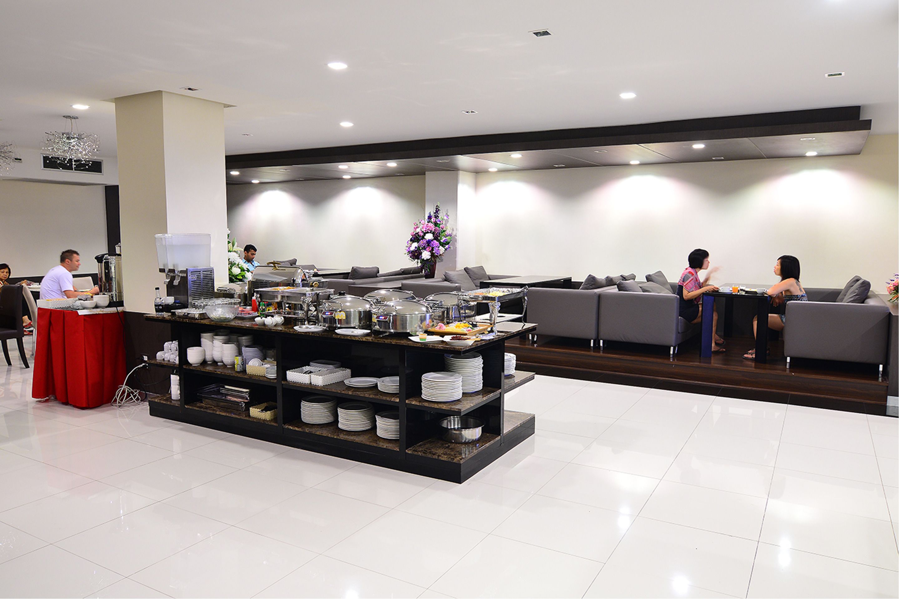 A modern hotel lobby with a buffet area, seating arrangements, and a decorative centerpiece.