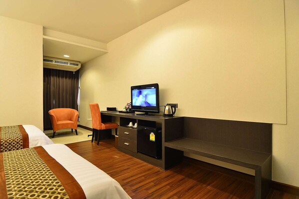 Una habitación de hotel con una cama, un escritorio con televisor, una silla y una cafetera.