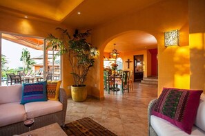 A spacious indoor area with a dining table, chairs, a sofa, and a large potted plant.